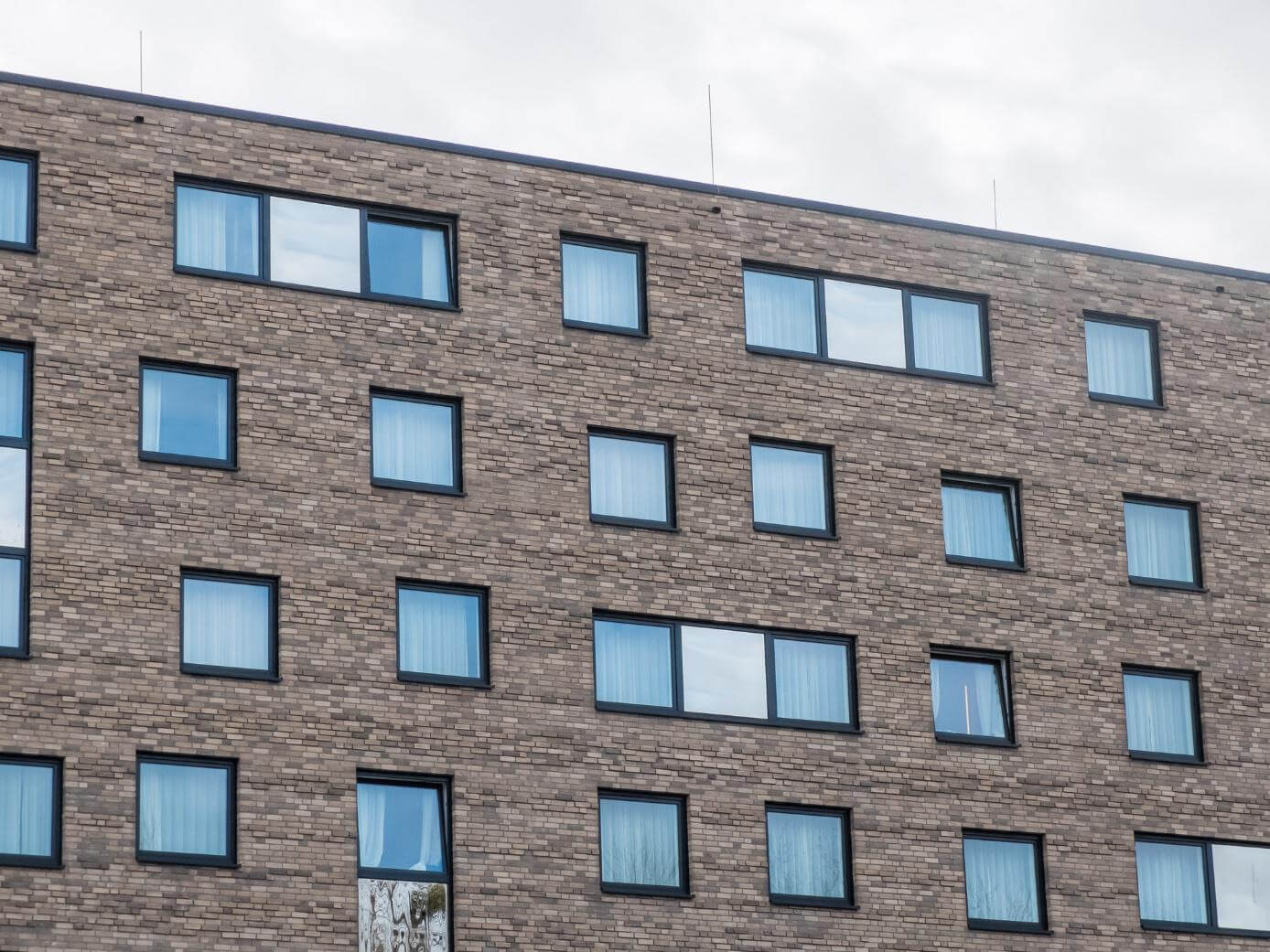 Mehrstöckiges Gebäude mit Klinkerfassade und quadratischen Kunststofffenstern