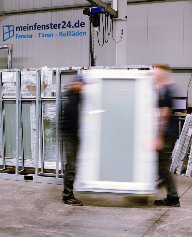 Foto aus dem Lager von meinfenster24 mit 2 Menschen, die ein Fenster tragen.
