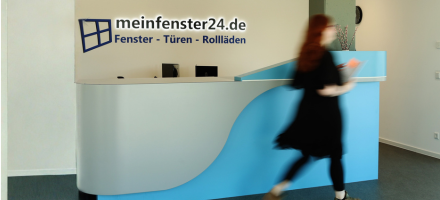 Foto des Eingangsbereichs von meinfenster24 in Apensen mit Mitarbeiterin, die durch das Bild läuft.