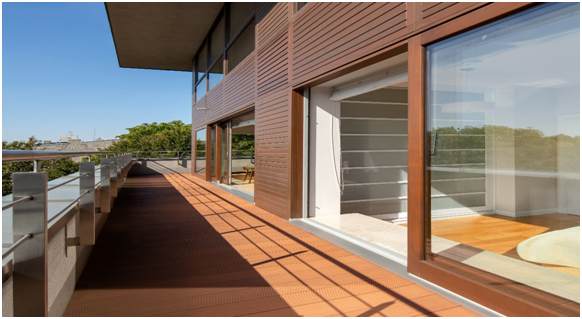 Umlaufender Balkon um das Gebäude mit offener Balkontür aus Holz