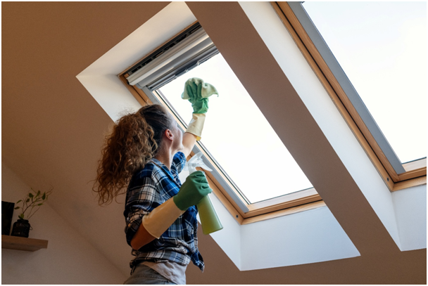 Frau reinigt Dachfenster