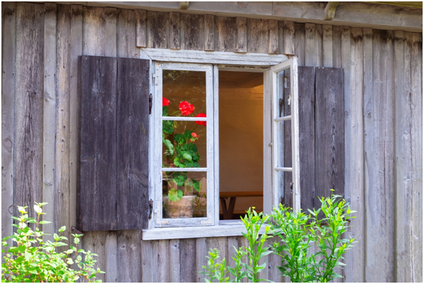 Blick von außen in ein geöffnetes Gartenhaus-Fenster aus Holz