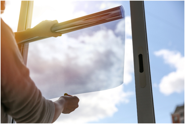 Mann bringt nachträglich Milchglasfolie an Fenster an.