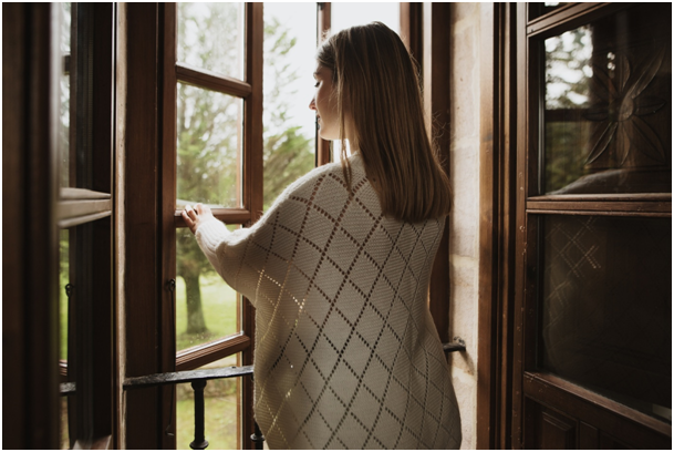 Ge&ouml;ffnetes Holzfenster mit einer Person, die die Fensterfl&uuml;gel nach au&szlig;en bewegt