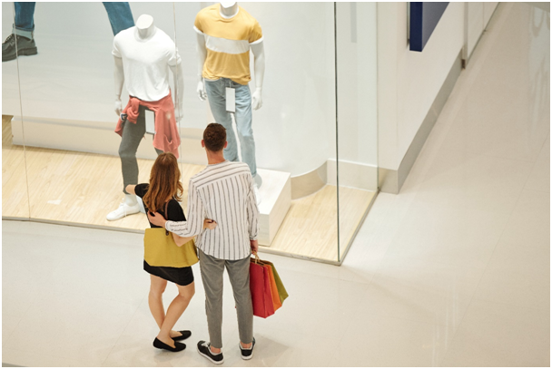 Pärchen steht Arm in Arm vor einem Schaufenster