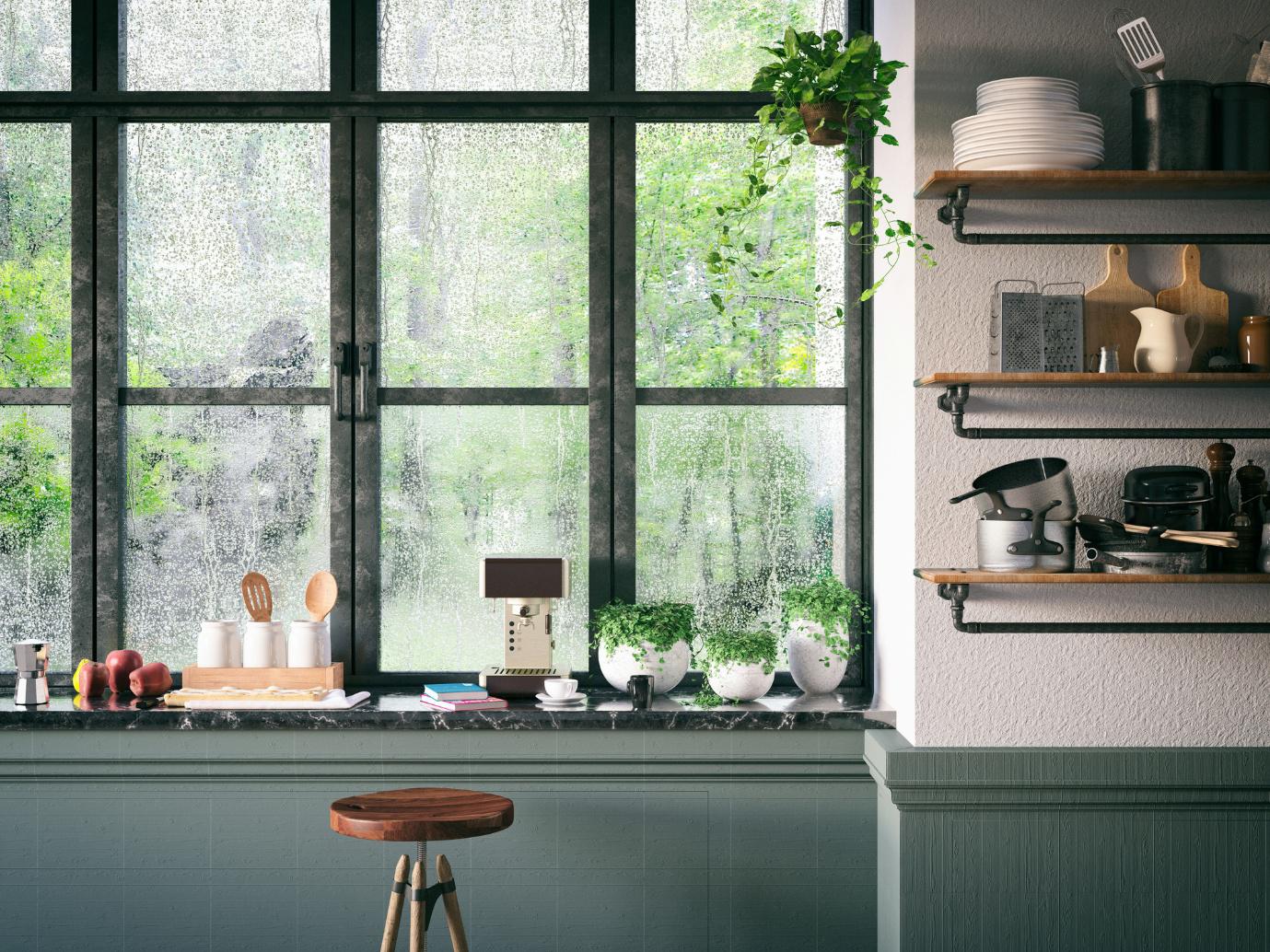 Moderne Küche mit großem Fenster, beschlagenen Scheiben, Zimmerpflanzen und Kaffeemaschine auf der Fensterbank.