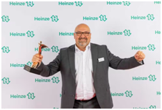 Özcan Arslan hält den Architects' Darling Award und blickt in die Kamera