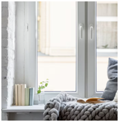 Fenster mit Fensterbank, darauf Bücher, Pflanze und gestrickte Decke