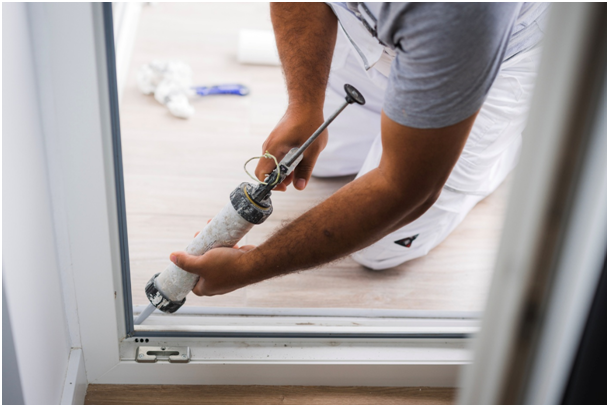 Handwerker dichtet eine T&uuml;rschwelle mit Silikon ab