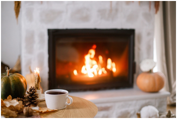 Gem&uuml;tliche Wohnzimmerszene mit brennendem Kamin, herbstlicher Dekoration und einer Tasse Tee