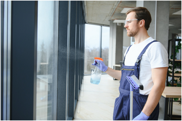 Mann reinigt bodentiefe Fenster