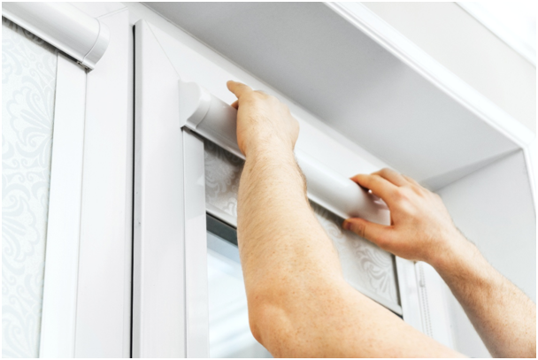 Mann installiert eine Kassettenrollladen an Fenster
