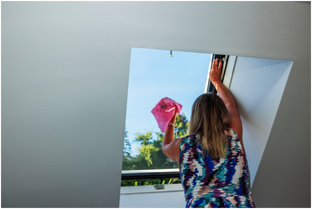 Frau putzt Dachfenster mit einem Tuch
