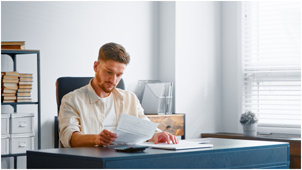 Mann sitzt an einem Schreibtisch und liest in einem Dokument