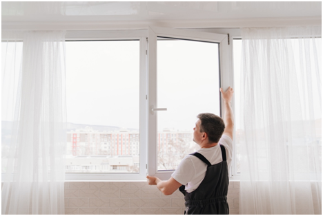 Handwerker beim Ausmessen eines Fensters, im Hintergrund ein Wohngebiet