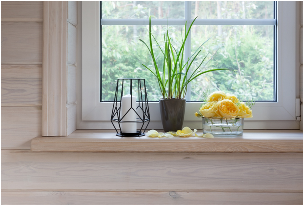 Fensterbank mit Kerze, Grünpflanze und Dekorationsblüten