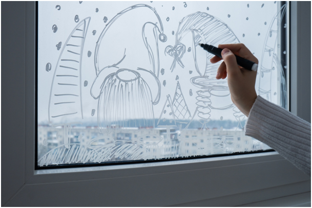 Fensterzeichnung aus Kreidemarker mit Weihnachtswichteln und Schnee