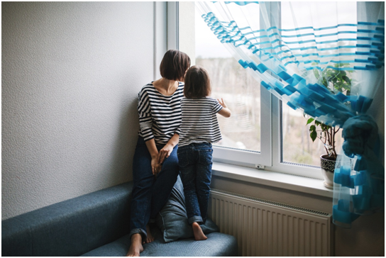 Mutter und Tochter schauen aus einem Fenster