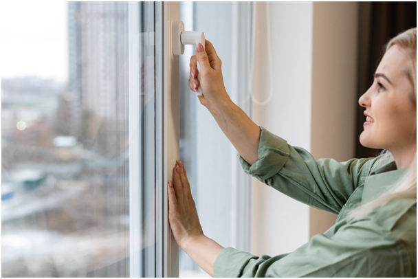 Frau, die einen Fenstergriff bedient