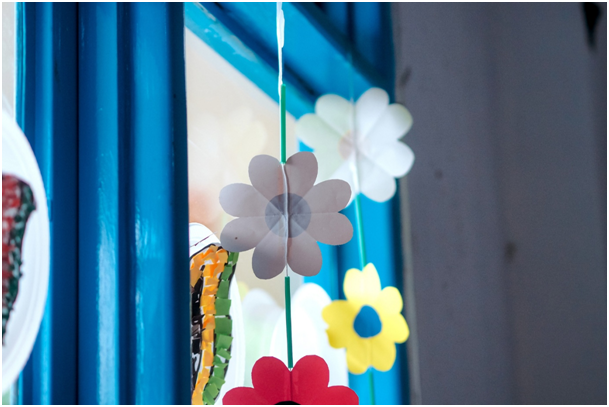 Selbstgebastelte Blumendekoration aus Papier vor einem Fenster