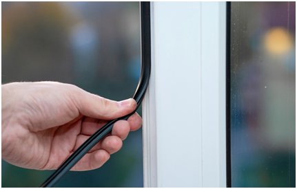 Hand drückt eine Dichtung in den Rahmen eines Fensters