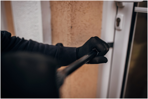 Person mit schwarzen Handschuhen hebelt eine T&uuml;r mit einem Brecheisen auf