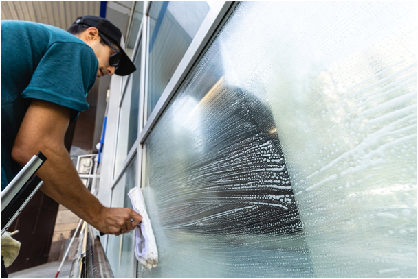 Mann reinigt Fensterglas mit Seifenwasser