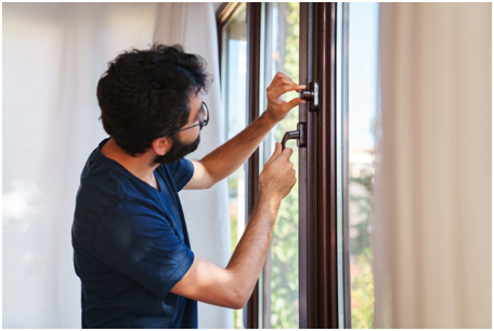 Seitenansicht eines Mannes, der an einem Holzfenster den Griff bet&auml;tigt.