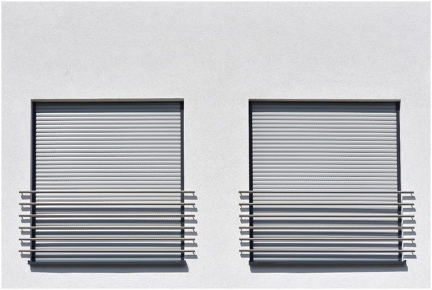 Zwei geschlossene Fenster mit Rollladen an Hauswand