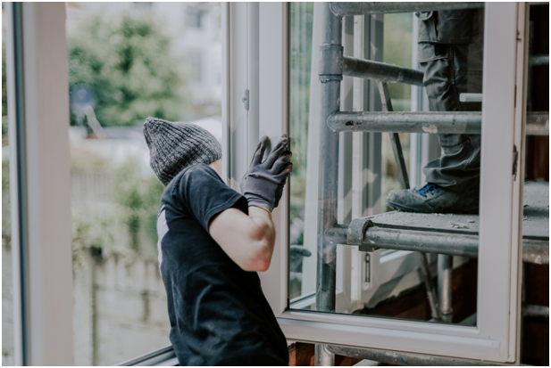 Handwerkerin setzt neues Kunststofffenster in einer Hausfassade ein