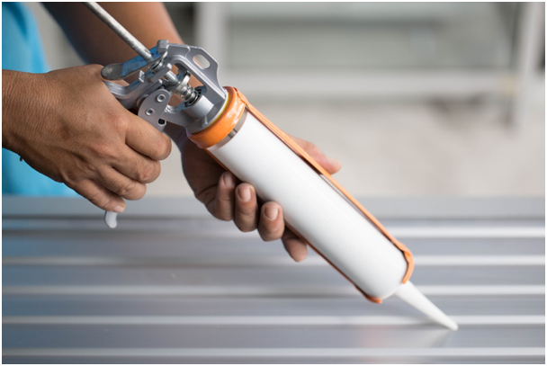 Mann dichtet Fensterfuge mit Silikonspritze ab