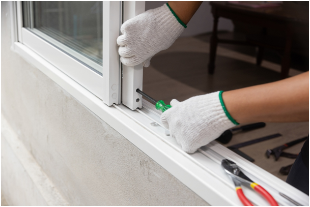 Ein Handwerker repariert ein Schiebefenster mit einem Schraubendreher
