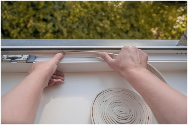 Person dr&uuml;ckt eine neue Dichtung in den Rahmen eines Kunststofffensters
