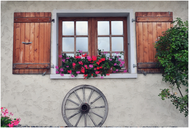 Eine Hauswand mit einem Holzfenster, Blumen und Dekor