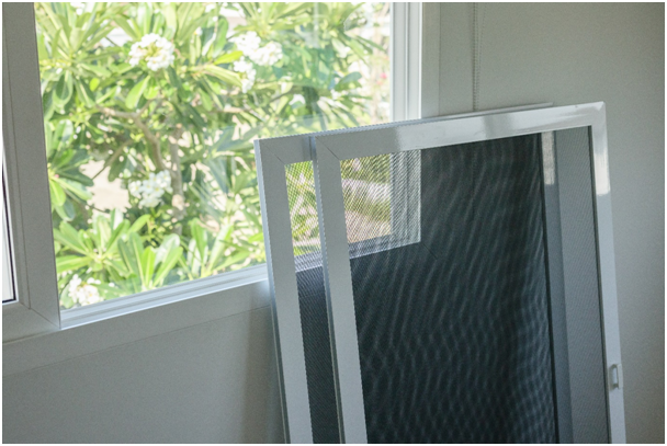 Zwei Fliegengitter sind an ein Fenster gelehnt.