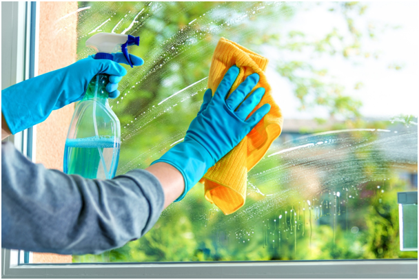 Fensterfl&auml;che wird in Handschuhen mit Reinigungsmittel und Tuch gereinigt