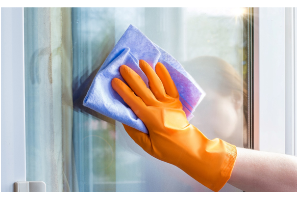 Frau putzt Fenster mit einem Tuch