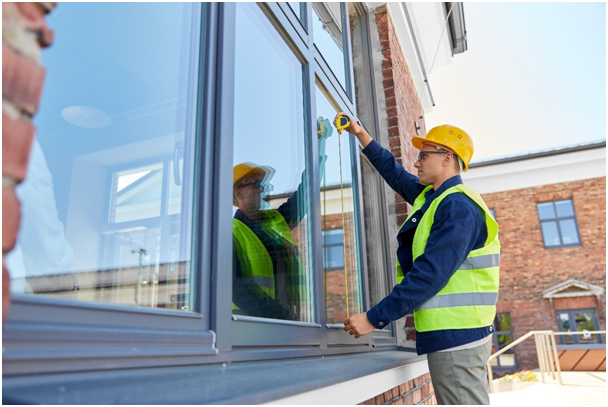 Monteur misst von au&szlig;en eine Fensterscheibe aus