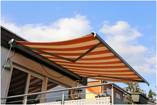 Orange-beige Markise &uuml;ber einem gr&ouml;&szlig;eren Balkon. Die Markise wirft einen Schatten.