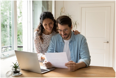 Paar &uuml;berpr&uuml;ft Steuerunterlagen am Laptop und freut sich &uuml;ber m&ouml;gliche Ersparnisse