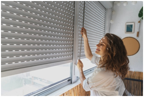Frau, die Rolll&auml;den auf dem Balkon &ouml;ffnet.