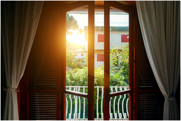 Ge&ouml;ffnete Balkont&uuml;r mit seitlich angebrachten Raffstores und Gartenblick