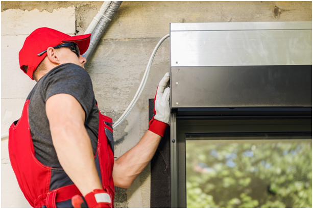 Handwerker montiert einen Rollladenkasten an einer Hausfassade