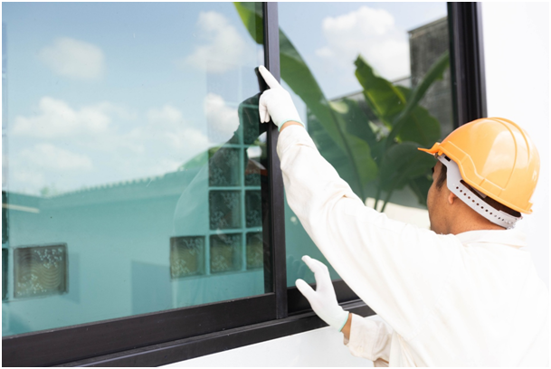 Fensterbauer, der mit dem Finger die Scheibe von au&szlig;en ber&uuml;hrt