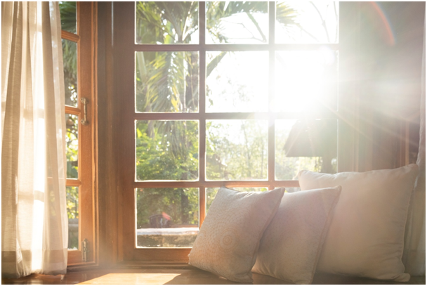Die Sonne scheint durch ein Wohnzimmerfenster, vor dem Kissen platziert sind