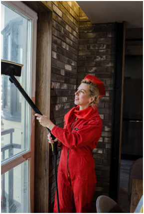 Eine Frau putzt das Fenster mit einem Dampfreiniger