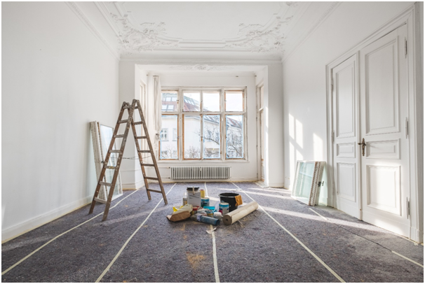 Blick in einen großen Raum mit einer Leiter und Sanierungsmaterial auf dem Boden