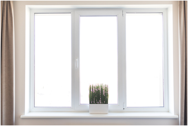 Modernes wei&szlig;es Kunststofffenster mit Vorh&auml;ngen und Pflanze auf Fensterbank