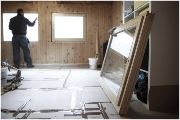 Alt-Attribut: Mann am Fenster im Hintergrund, im Vordergrund aufgestelltes und abmontiertes Fenster.