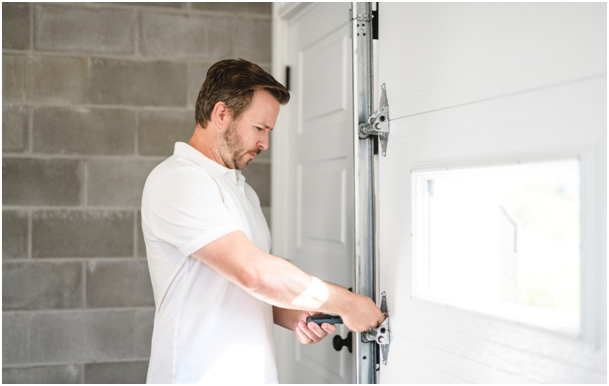 Mann montiert Nebeneingangst&uuml;r neben Garage.